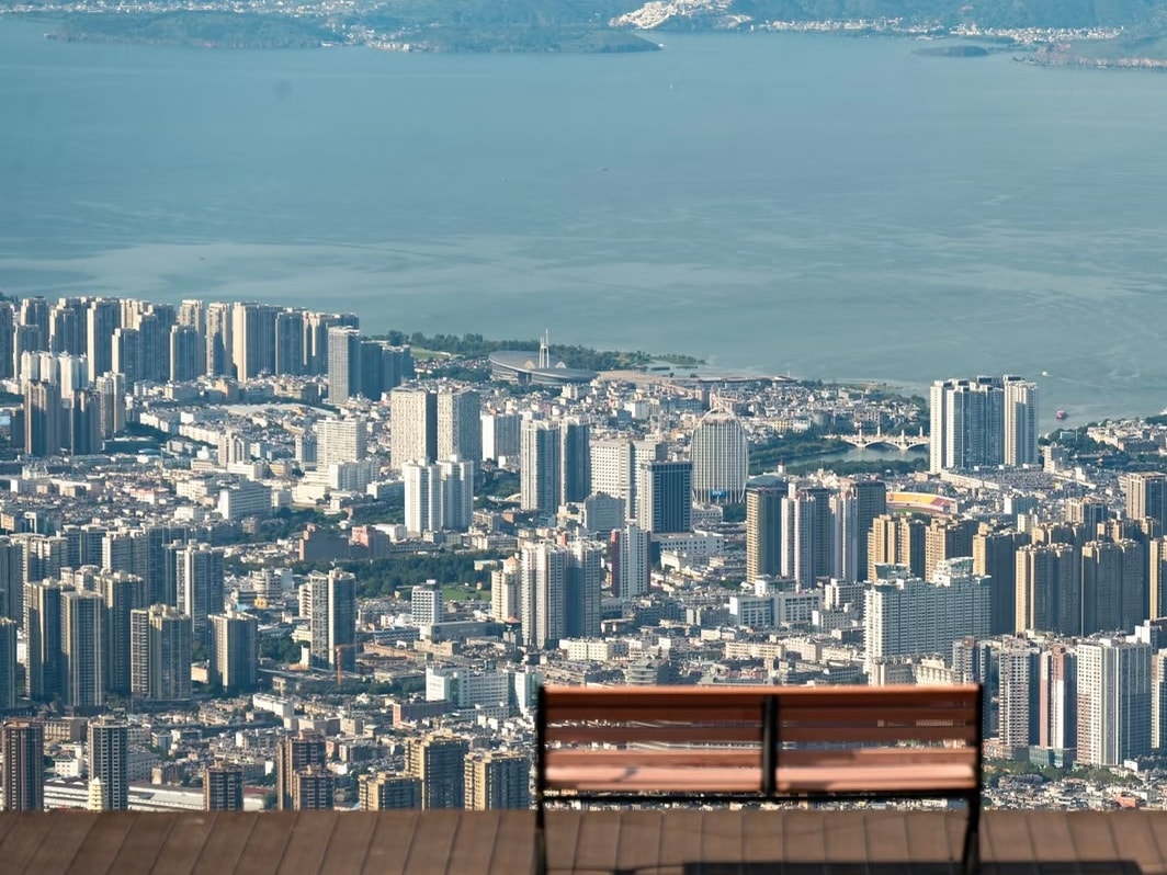 Wooden bench on a viewing deck high above Dali city, with Erhai Lake beyond