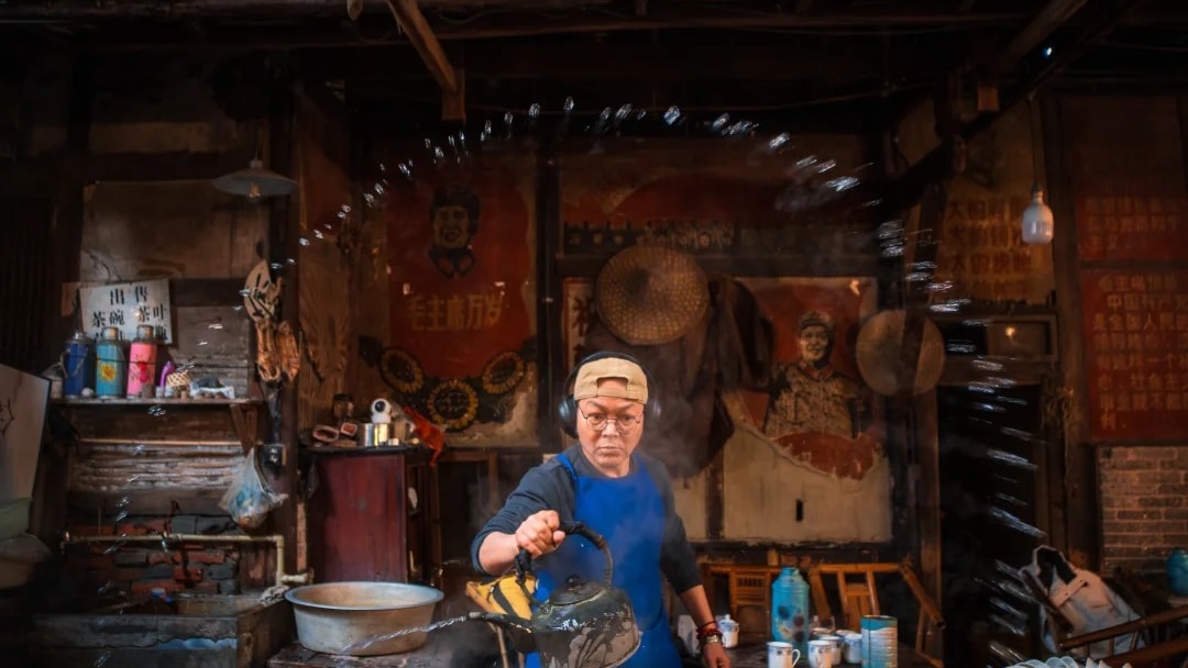 A tea master pouring from a long-spouted copper kettle among tea urns in an old Sichuan teahouse.