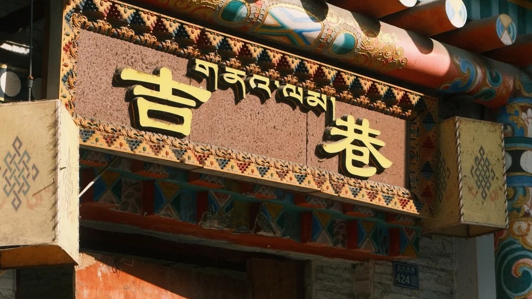 A painted Tibetan-style gateway with carved beams over a lane in Kangding.