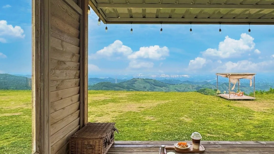 A wooden cafe terrace with director's chairs looking out over a green mountain ridge.