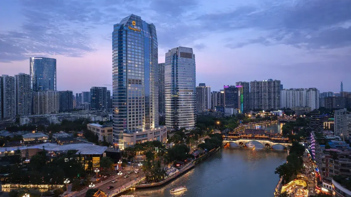 The Shangri-La Chengdu tower above the Jin River and the city skyline at dusk.