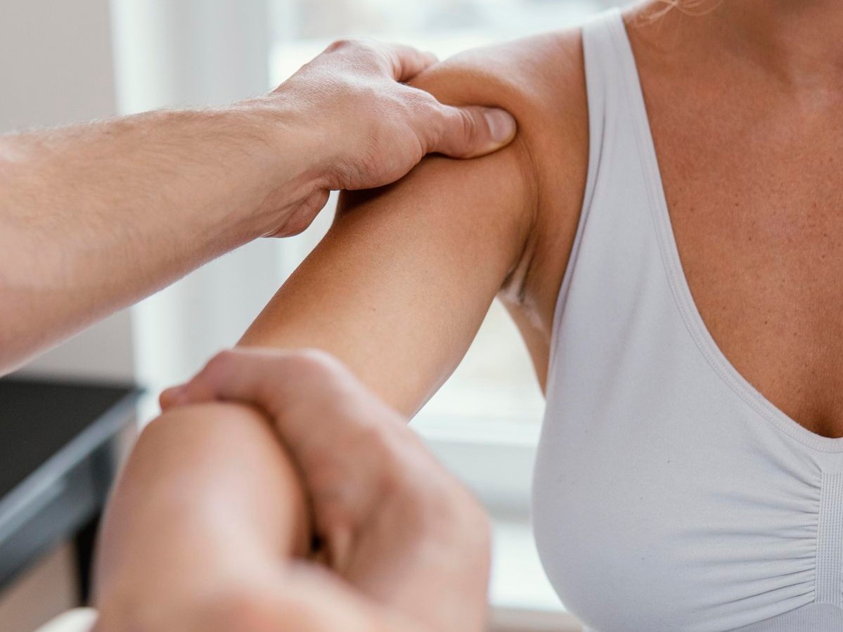 Therapist assessing a client's shoulder and arm