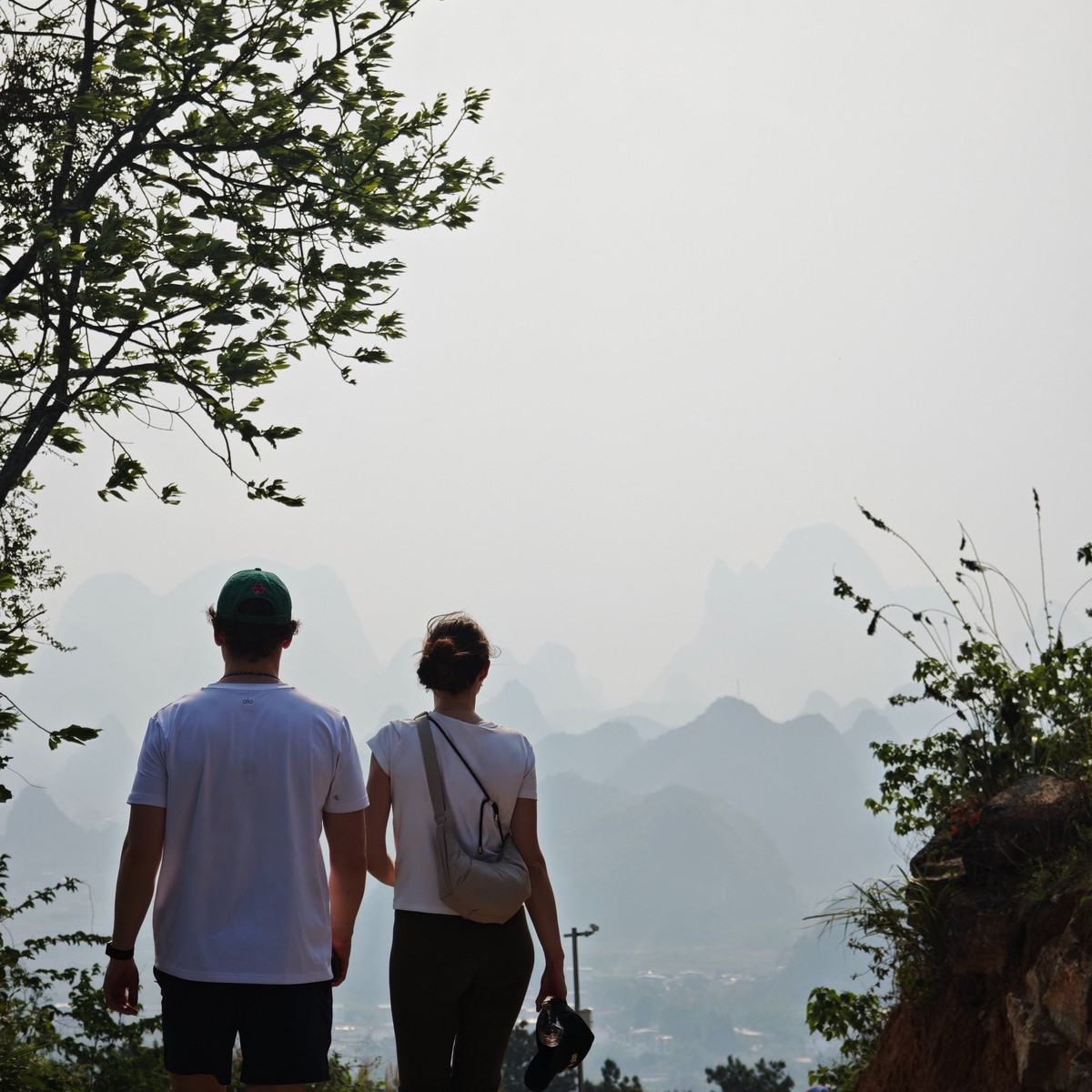 Two guests walking a dirt track towards hazy karst peaks