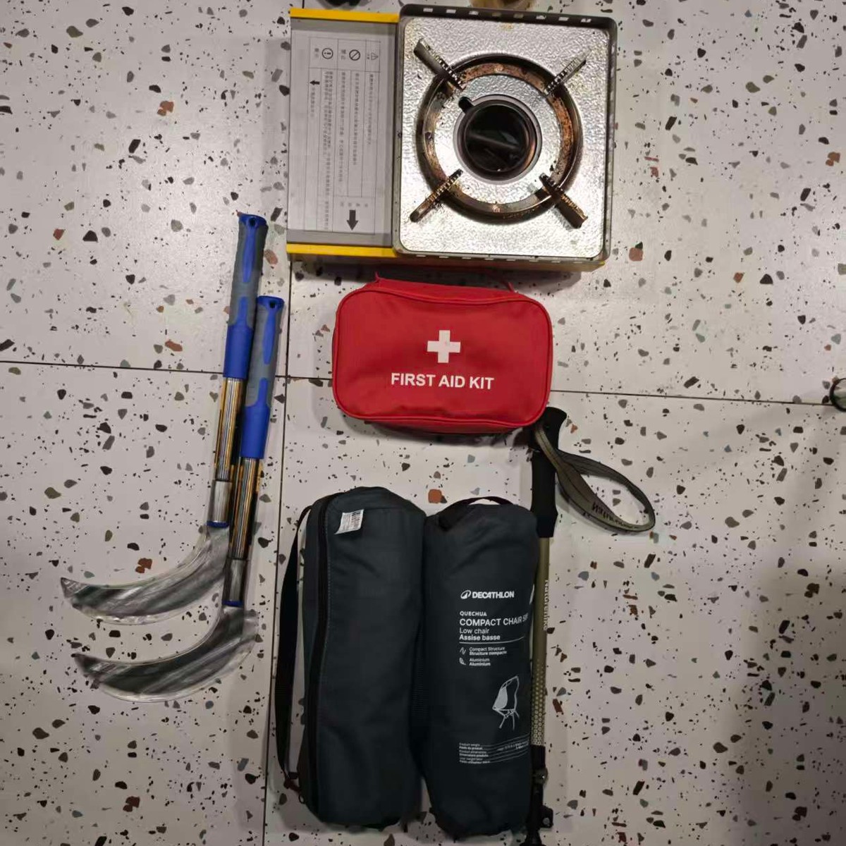 Support kit laid out: camp stove, first-aid kit, trekking poles and folding chairs