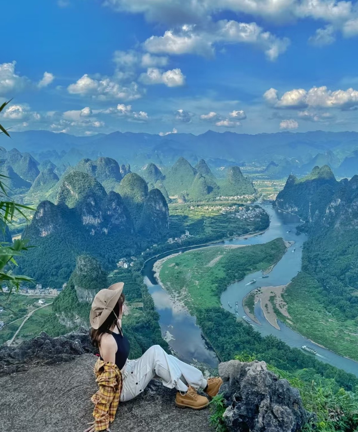 Guest sitting on the summit rock looking down at the river bend and its sandbars
