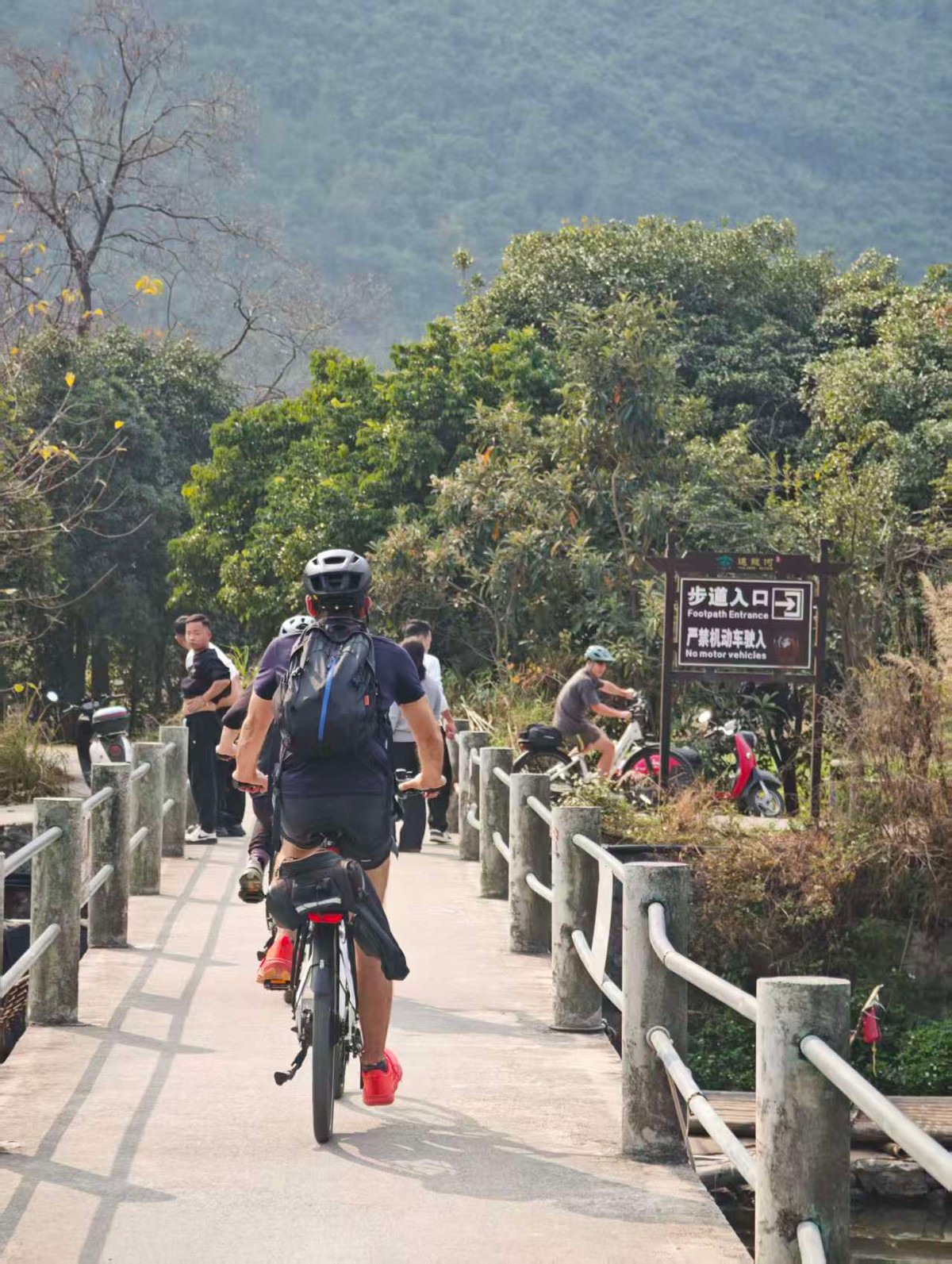 Riders crossing a bridge at the footpath entrance to the river trail