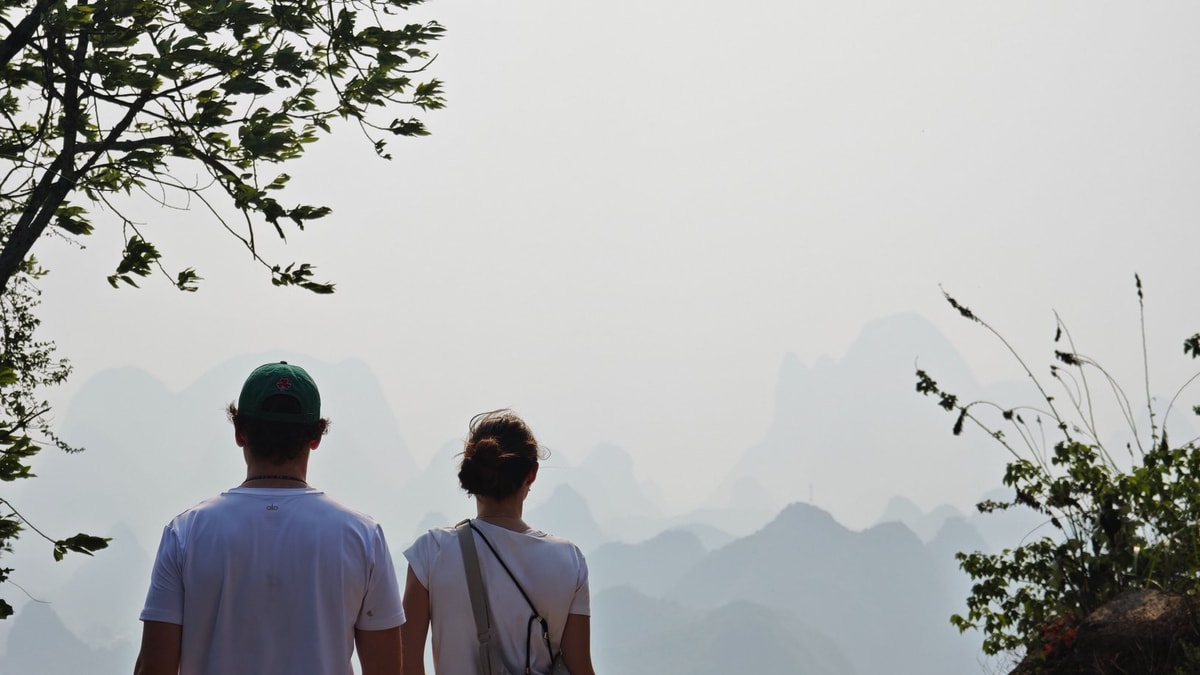 Two guests walking a dirt track towards hazy karst peaks