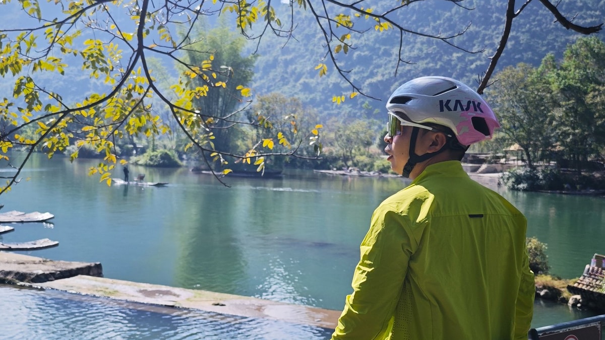 Rider pausing at the railing above a raft landing, moored bamboo rafts below