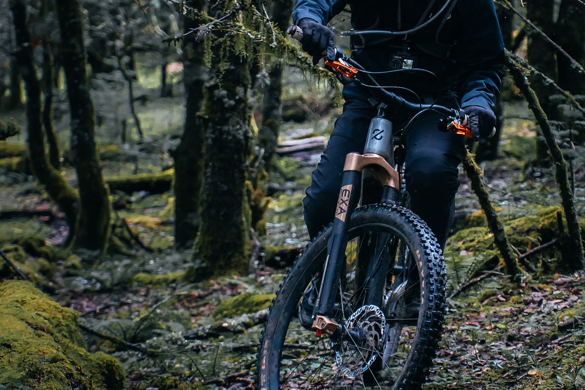 Close-up of a rider on an Amflow e-MTB with a gold suspension fork on a mossy forest trail