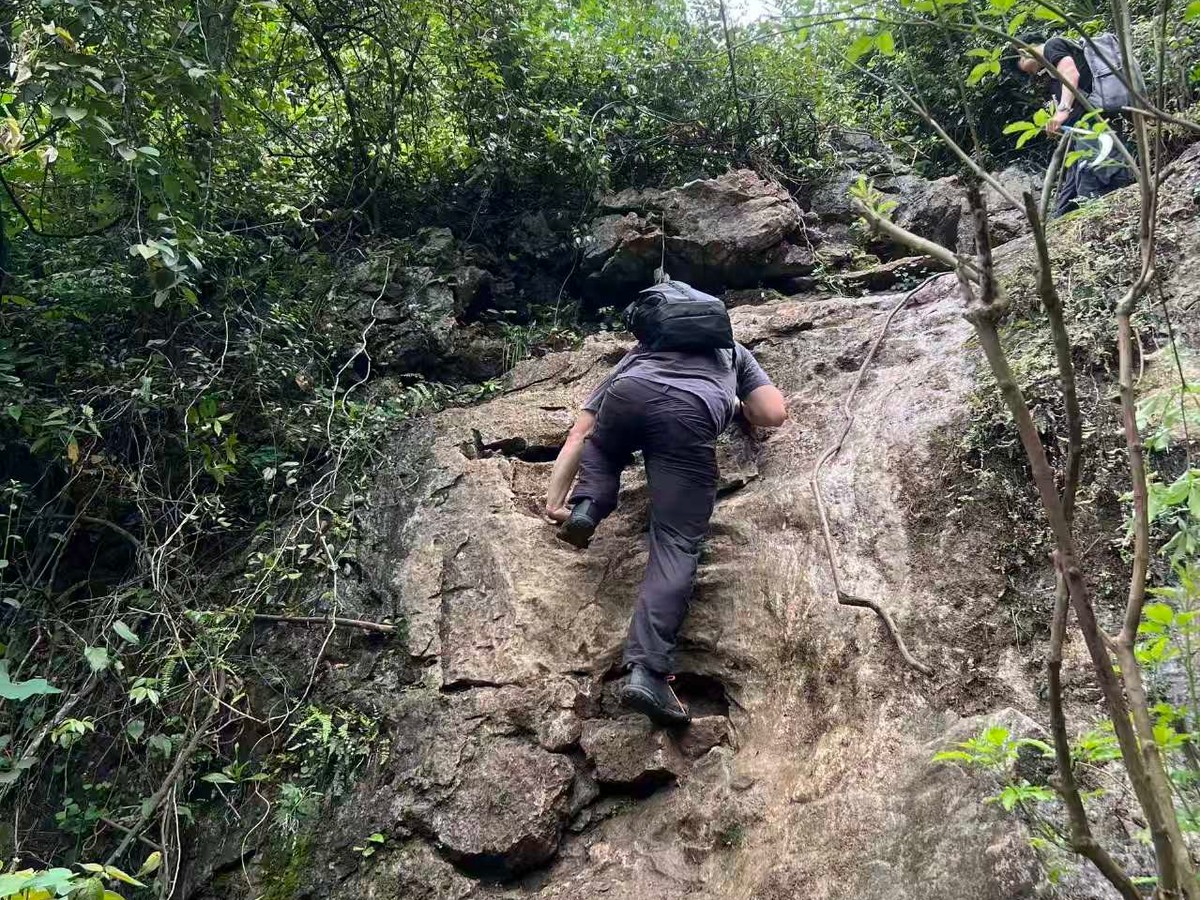 Rider scrambling up a bare rock slab on the wooded hiking trail