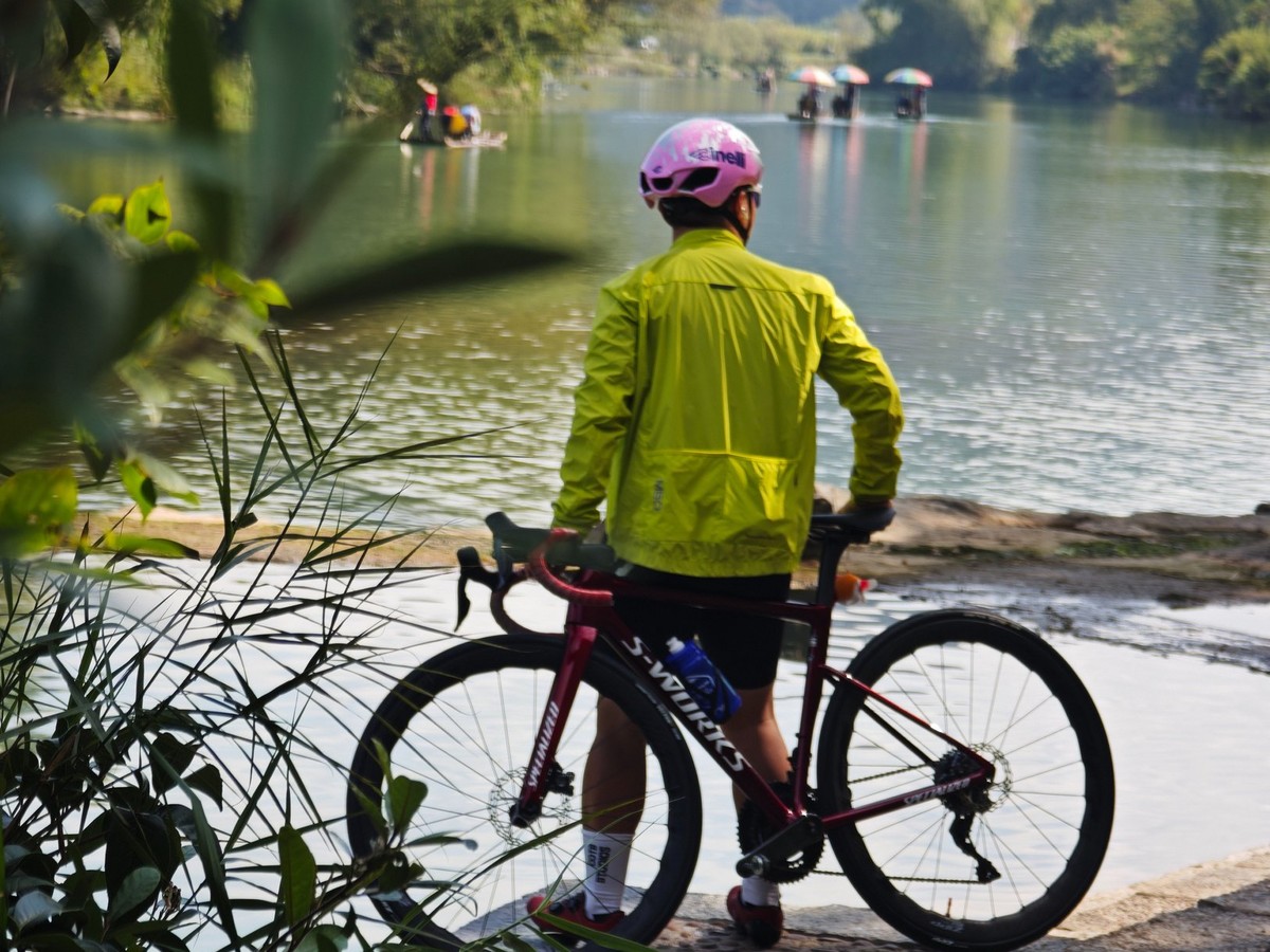 Rider looking out over the river as bamboo rafts drift past