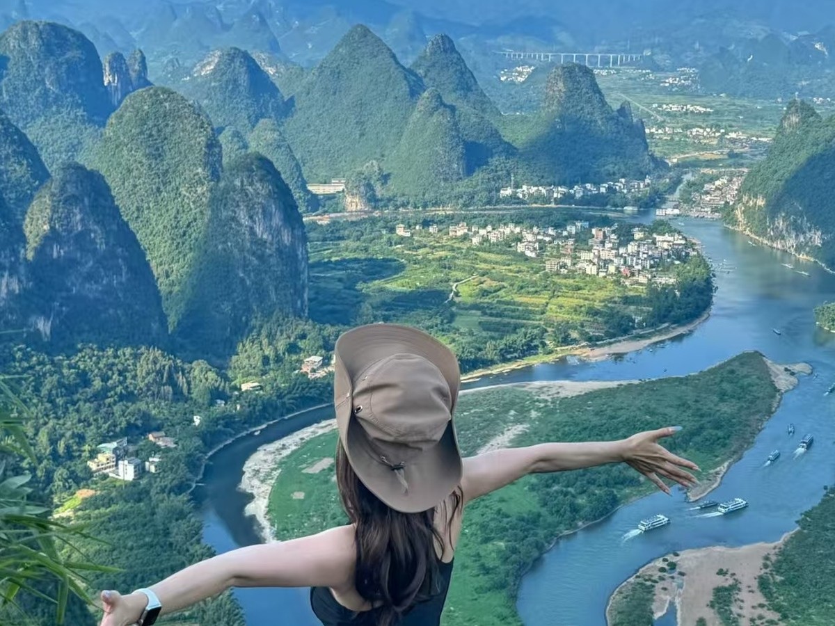 Guest with arms outstretched on a summit rock above the river's horseshoe bend
