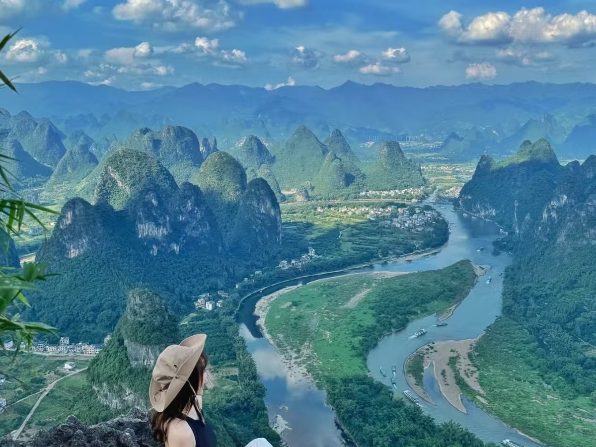 Guest sitting on the summit rock looking down at the river bend and its sandbars
