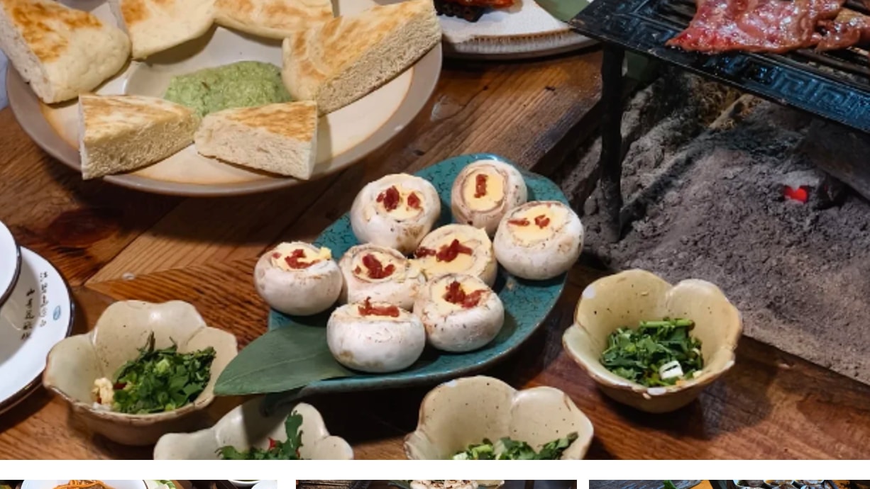 Table spread of traditional firepit dining featuring grilled meats, stuffed mushrooms, and hot pot.