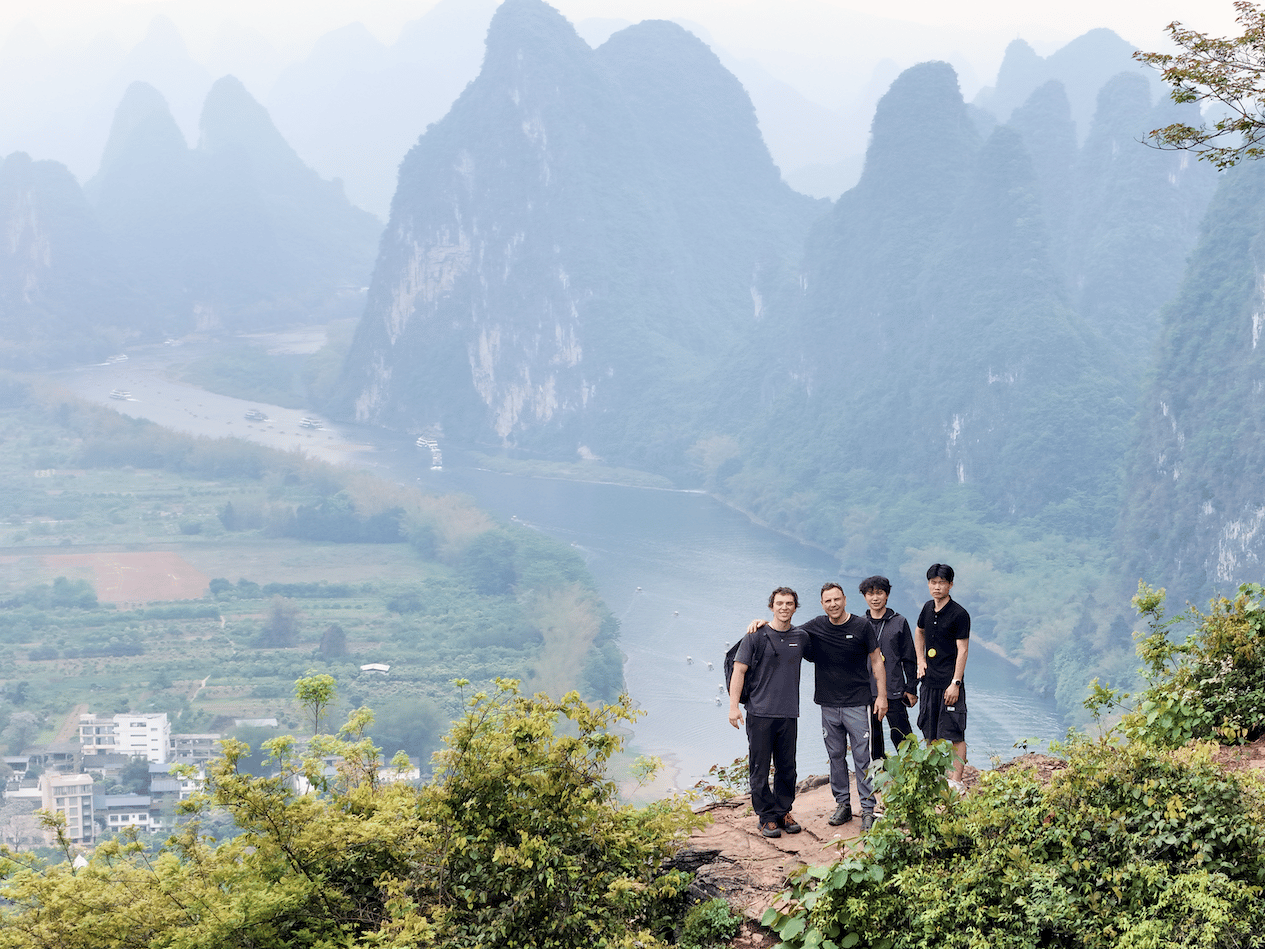 Four riders on a clifftop ledge high above the river bend