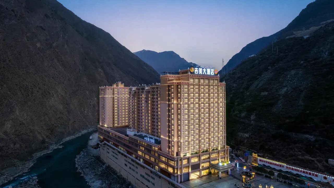 Danba Jimei Hotel lit at dusk beside the river in its steep mountain gorge.
