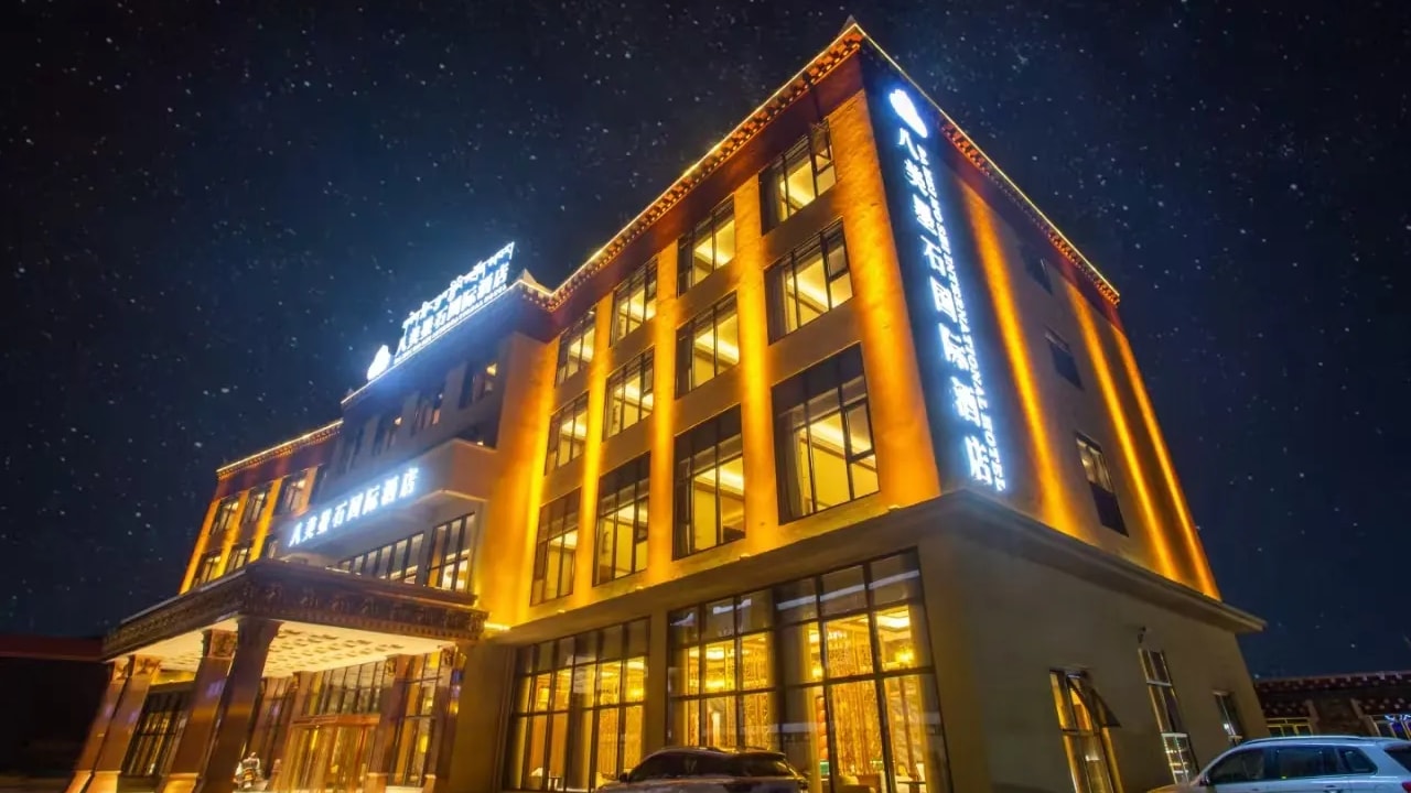 Bamei Moshi International Hotel lit warmly against the night sky on the Tibetan plateau.