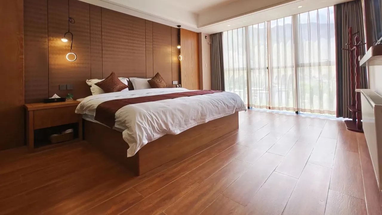 A bright contemporary guest room with a wooden floor and a wide window onto the mountains.