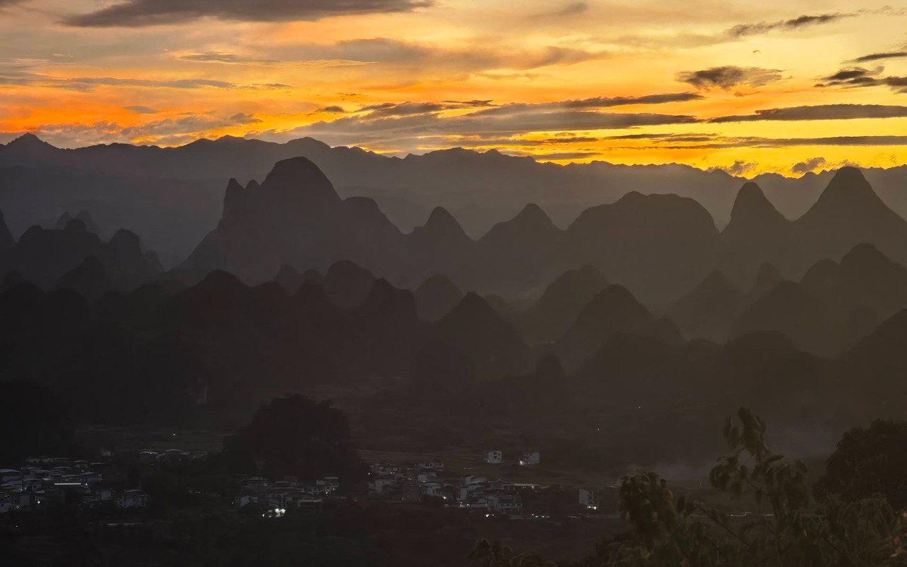 Sunset over layered karst ridges along the Thousand River and Mountain viewpoint corridor between Guilin and Yangshuo