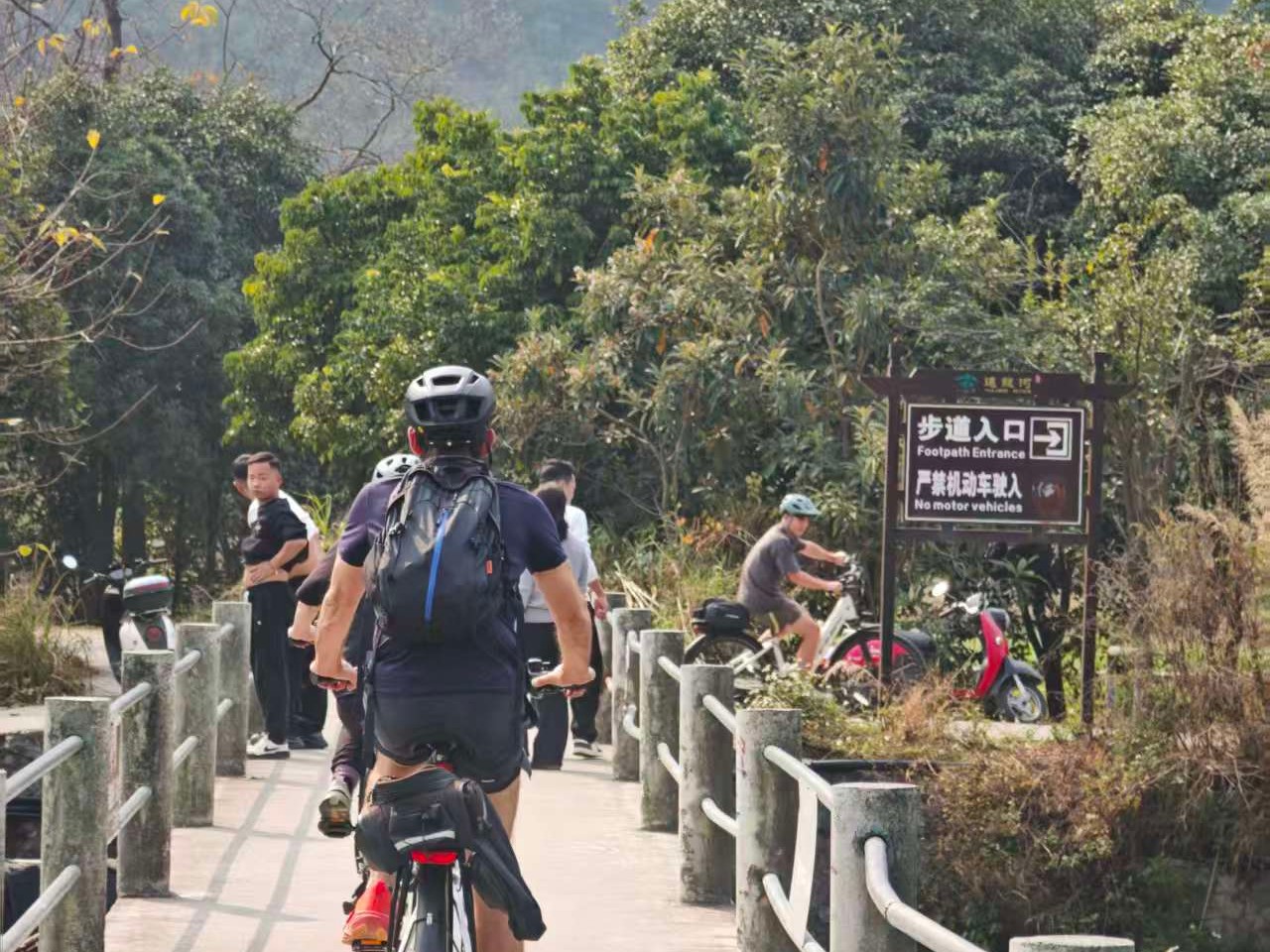 Riders crossing a bridge at the footpath entrance to the river trail