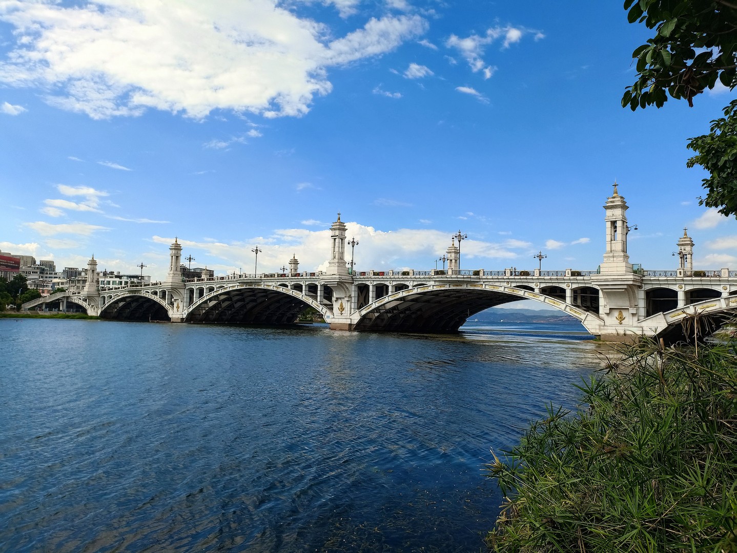 Arched Xingsheng Bridge spanning the Xi'er River in Xiaguan under a blue sky
