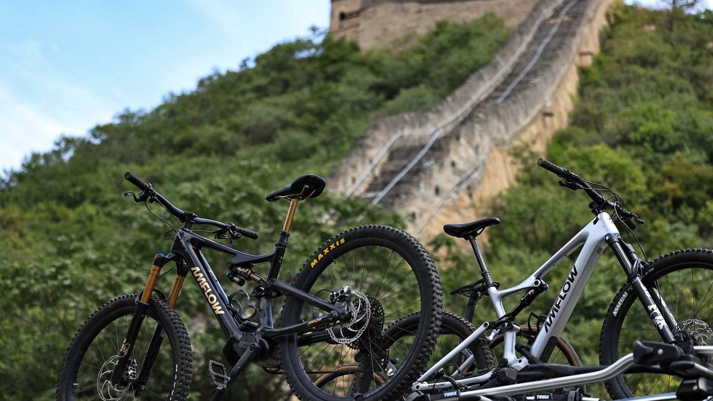 Ancient Great Wall of China winding through lush green mountains under a bright blue sky.