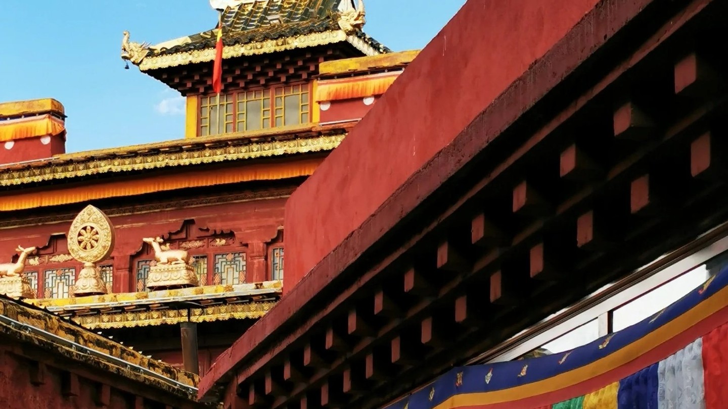 A gold-roofed temple and red-walled street hung with prayer flags in a Tea Horse Road town.