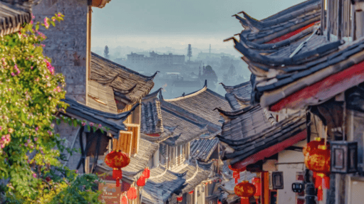 Scenic narrow street in Lijiang Old Town with traditional tiled roofs and red Chinese lanterns.
