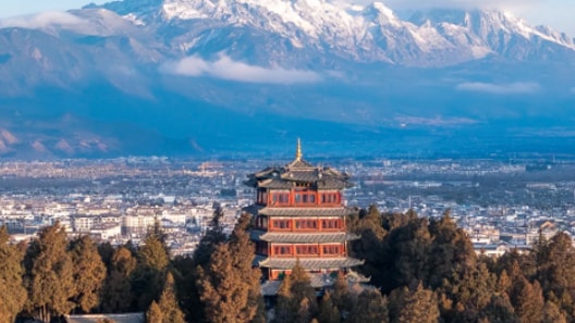 Ancient Chinese pagoda in Lijiang Old Town with the snow-capped Jade Dragon Snow Mountain in the background.