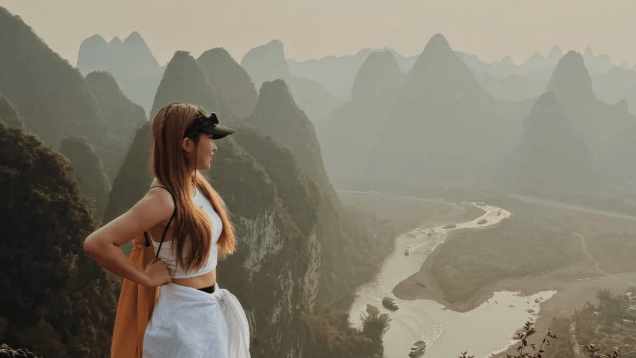 Guest standing on the summit looking out over the hazy river valley