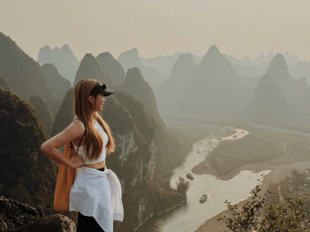 Guest standing on the summit looking out over the hazy river valley
