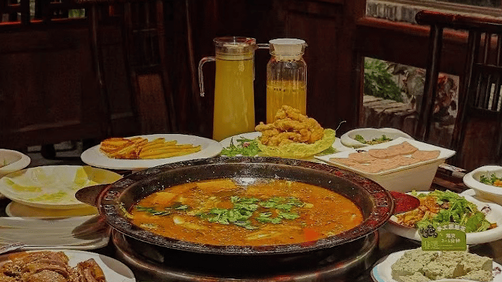 A Sichuan banquet table set with a large fish hotpot and rows of side dishes.
