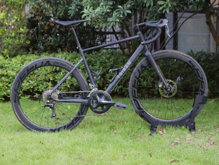 A matte black Triban RC500 road bike with deep section carbon wheels parked on a green lawn.