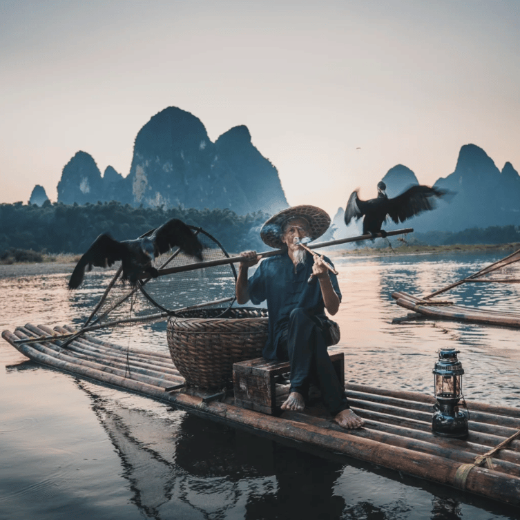 Traditional cormorant fisherman on a bamboo raft at sunset on the Li River at Xingping