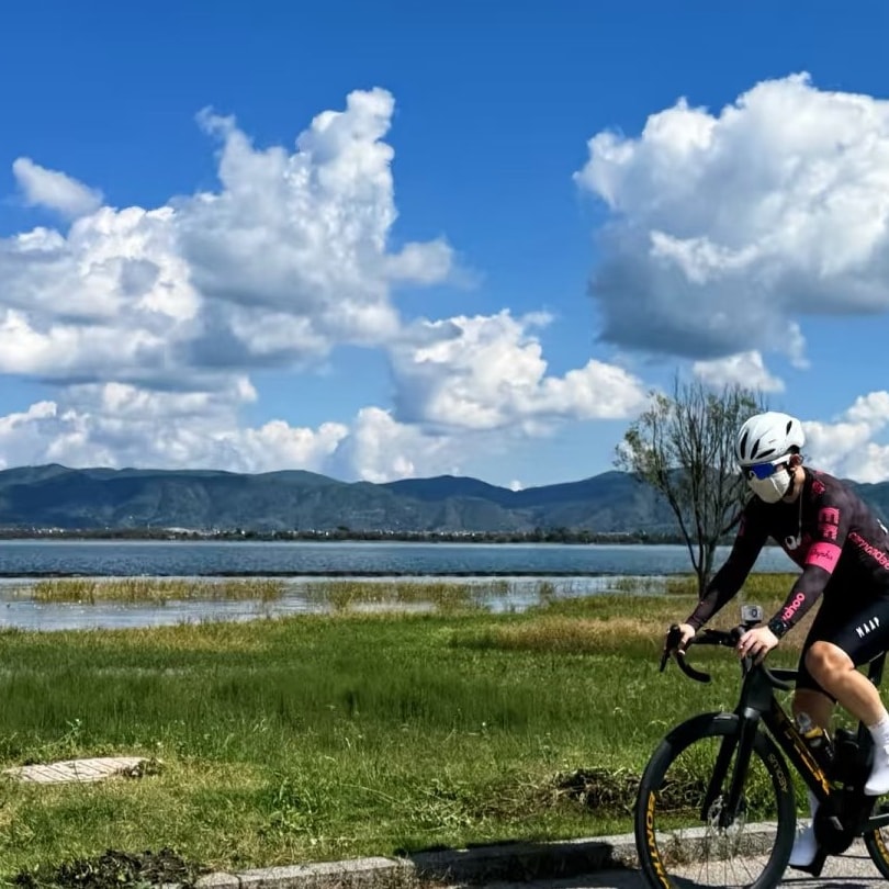 Cyclist on the grassy lakeside greenway with Erhai and distant hills behind
