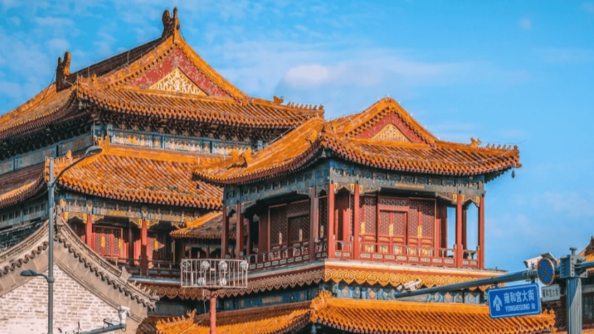 Traditional Chinese palace architecture with orange roof tiles against a blue sky in Beijing.