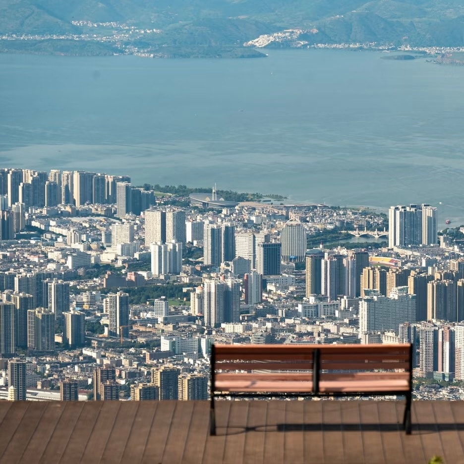 Wooden bench on a viewing deck high above Dali city, with Erhai Lake beyond
