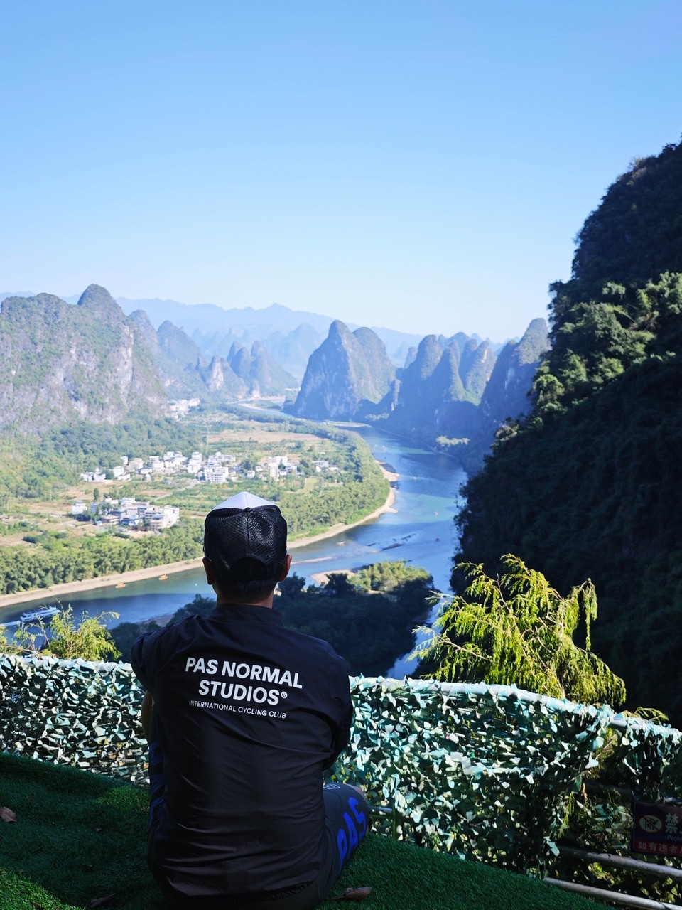 Rider resting at a turfed viewing terrace above the river bend and karst valley