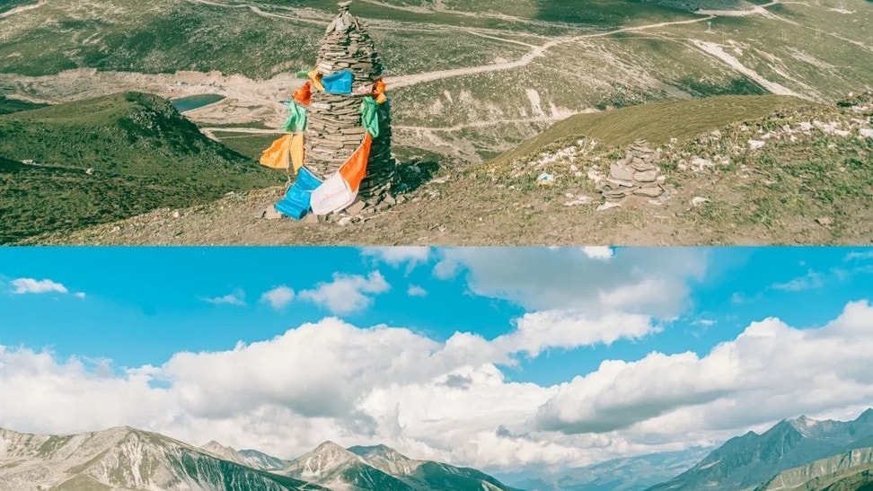 Prayer flags at a high pass above winding mountain roads and open highland valleys.